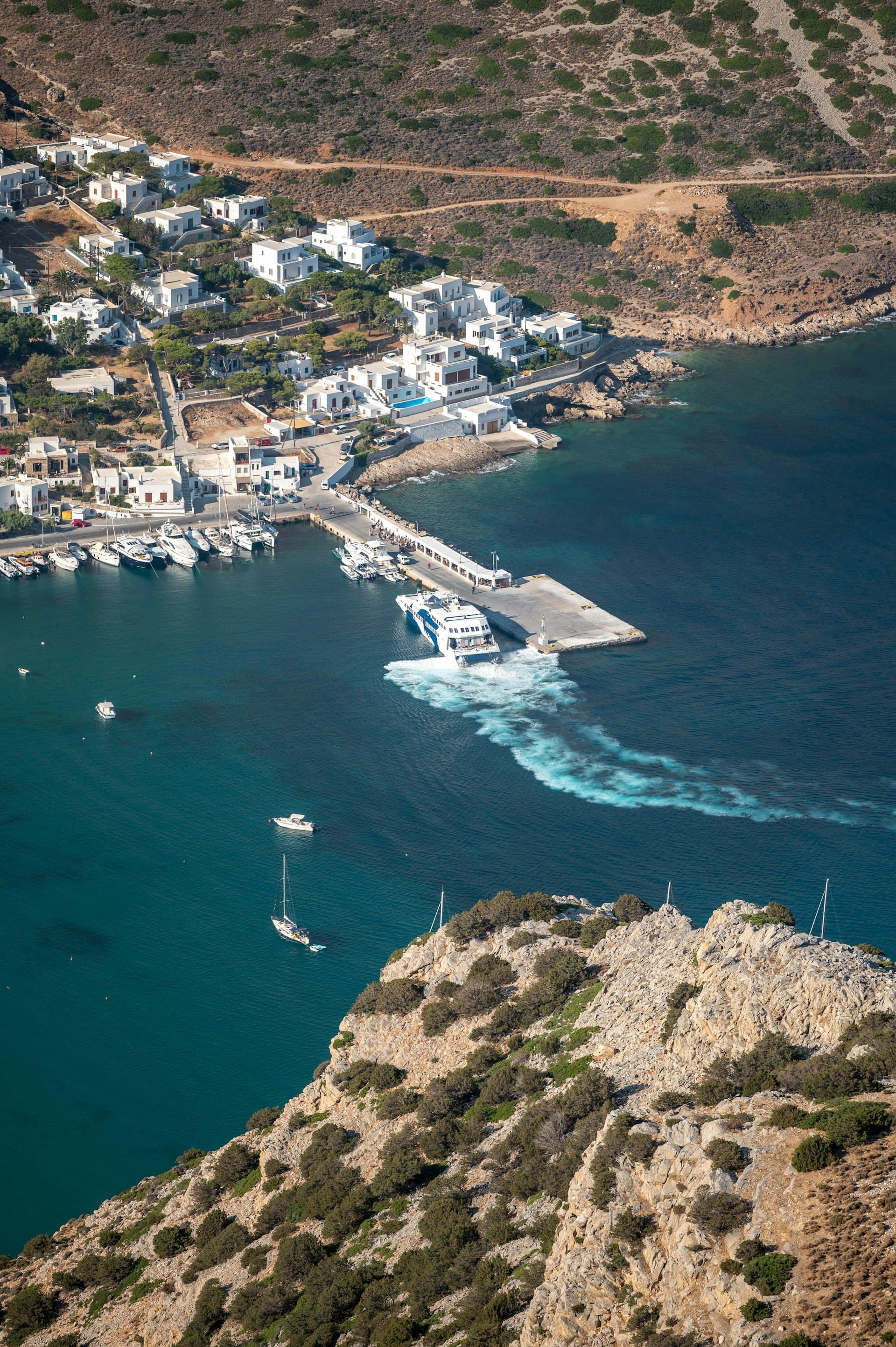 A Greek island harbour with white houses above turquoise water