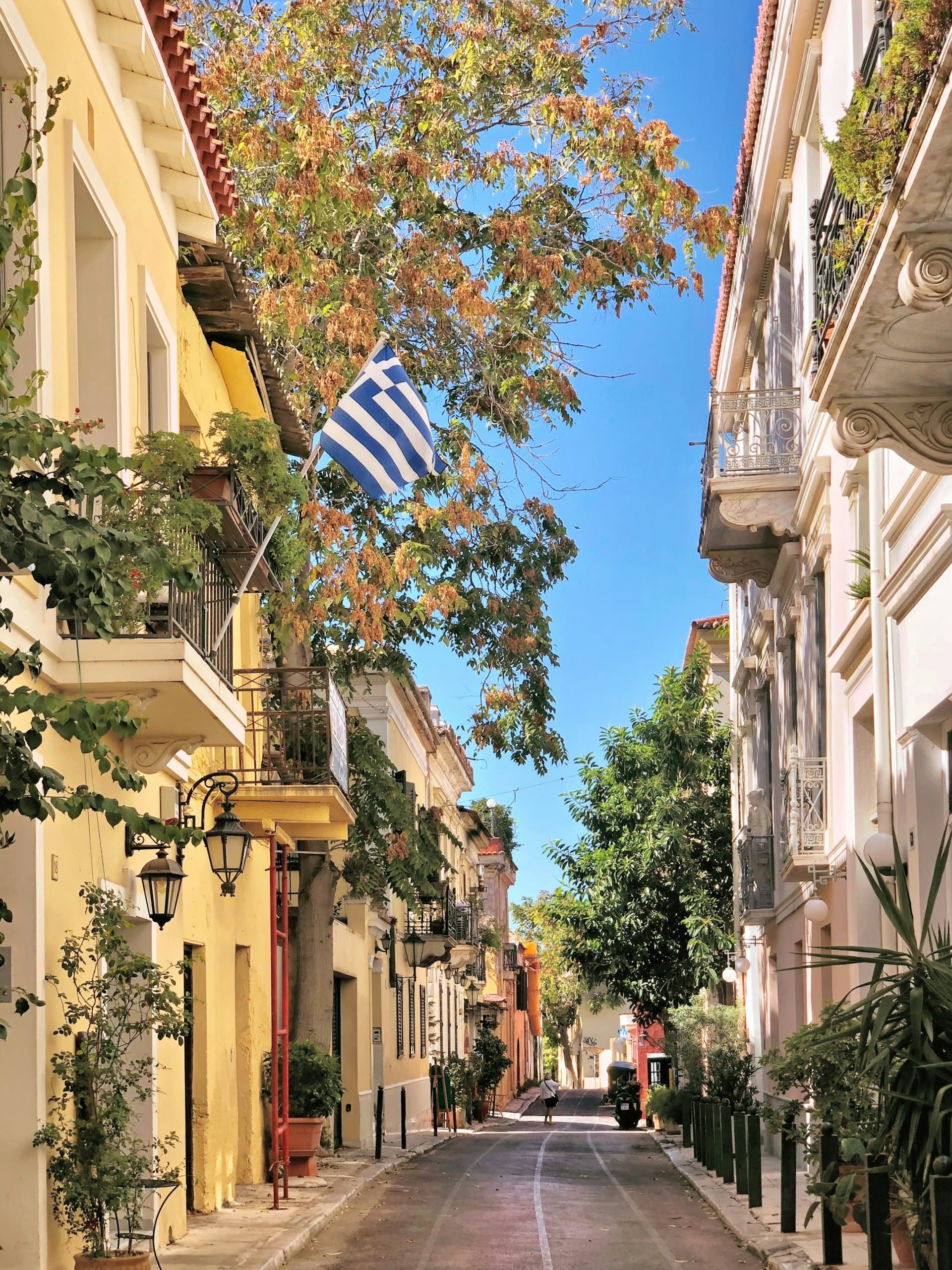 A quiet neoclassical street in the Plaka district of Athens with a Greek flag